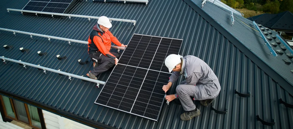 Técnicos reparando placas solares en el tejado de una casa